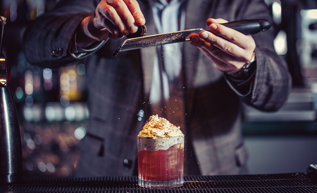 Grating nutmeg over a cocktail